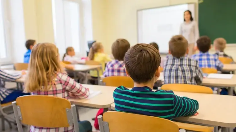 Dzieci siedzące w ławkach na lekcji w szkole