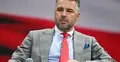 Michał Rachoń z mikrofonem na tle ekranu z biało-czerwoną flagą