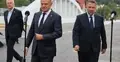 Politycy w garniturach na konferencji prasowej. W tle most