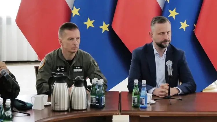 Gen. Ireneusz Nowak, Władysław Kosiniak-Kamysz siedzą przy stole. W tle flagi Polski i UE