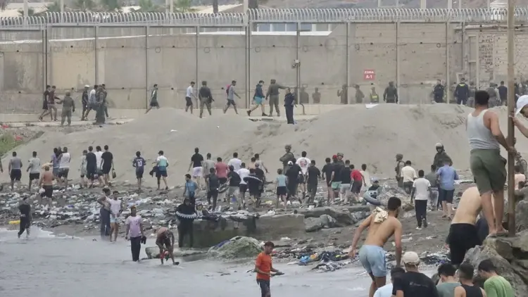 Migranci forsujący mur graniczny w Ceucie
