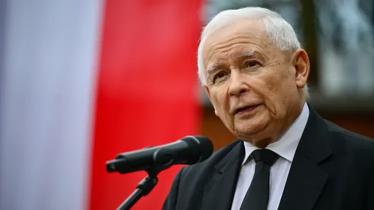 Jarosław Kaczyński przemawia do mikrofonu. W tle polska flaga