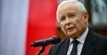 Jarosław Kaczyński przemawia do mikrofonu. W tle polska flaga