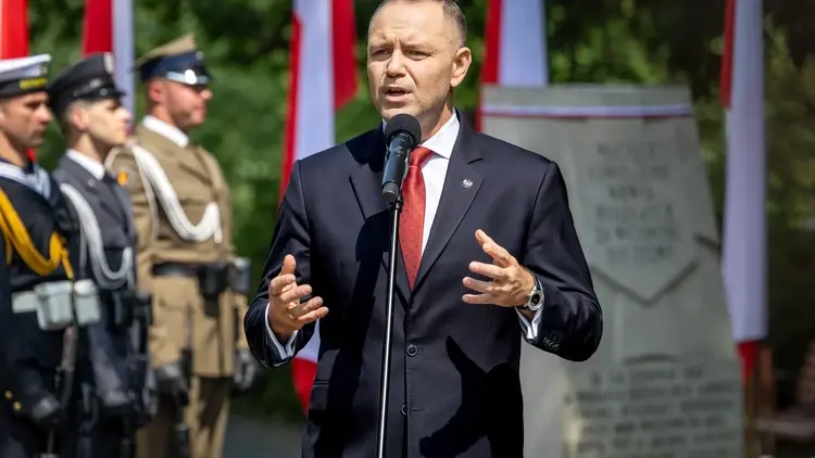 Karol Nawrocki przemawia na uroczystości. W tle żołnierze, polskie flagi i pomnik