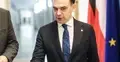 Andrzej Domański na korytarzu. W tle flaga Polski i UE