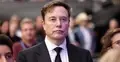 Elon Musk w garniturze, w tle i obok niego ludzie