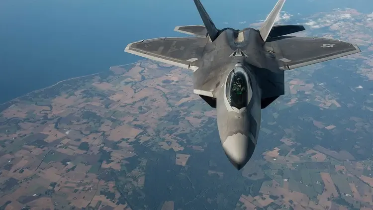 Amerykański myśliwiec F-22 w powietrzu. W tle ziemia