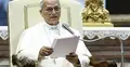 Papież Leon XIV przemawia do mikrofonu. Siedzi na fotelu, w ręku trzyma kartki