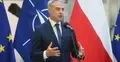 Krzysztof Gawkowski przemawia i gestykuluje. W tle flaga Polski, UE i NATO