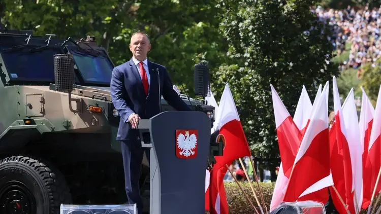 Karol Nawrocki przemawia, w te pojazd wojskowy, polskie flagi i drzewa