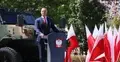 Karol Nawrocki przemawia, w te pojazd wojskowy, polskie flagi i drzewa