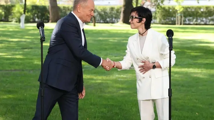 Donald Tusk i Barbara Mróz-Gorgoń ściskają sobie dłonie, w tle park