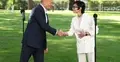 Donald Tusk i Barbara Mróz-Gorgoń ściskają sobie dłonie, w tle park