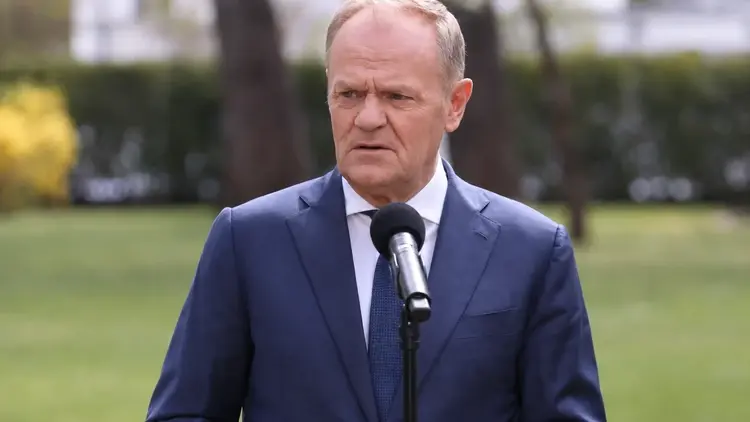 Donald Tusk przemawia do mikrofonu. W tle park