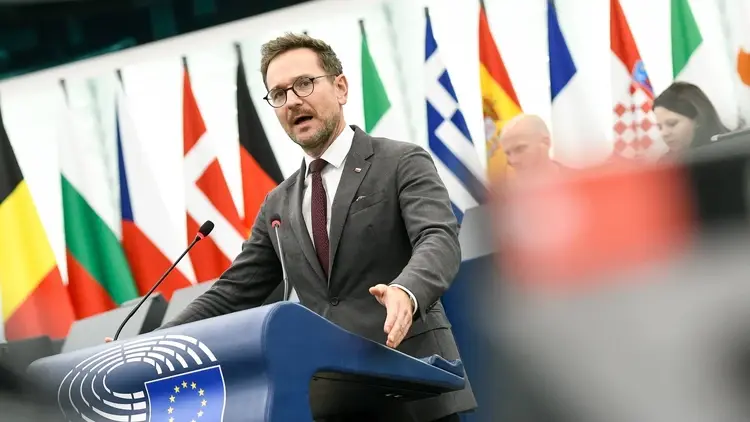 Waldemar Buda przemawia w PE, w tle flagi krajów UE