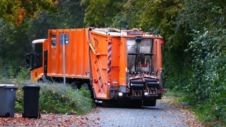 pomarańczowa śmieciarka w parku