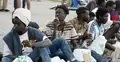 Migranci siedzący na plaży w Ceucie