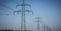 Słupy elektroenergetyczne na tle drzew nieba