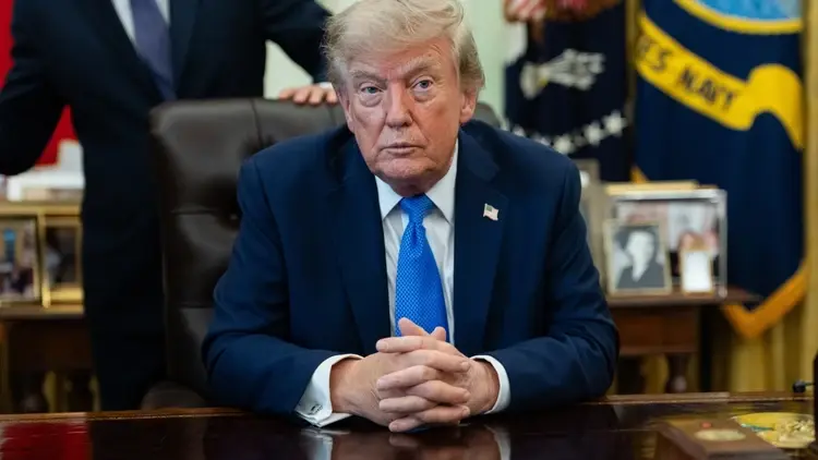 Donald Trump w Gabinecie Owalnym. Ręce trzyma skrzyżowane przed sobą