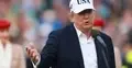 Donald Trump z czapką na głowie przemawia do mikrofonu i gestykuluje, w tle tłum