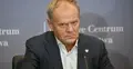 Donald Tusk siedzi przy stole, obok mikrofon