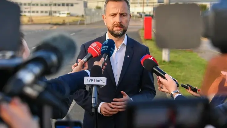 Władysław Kosiniak-Kamysz rozmawia z dziennikarzami. W tle baza wojskowa