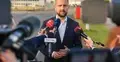 Władysław Kosiniak-Kamysz rozmawia z dziennikarzami. W tle baza wojskowa