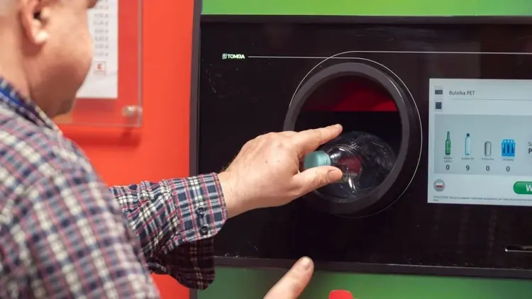 mężczyzna wrzuca butelkę do recyklomatu