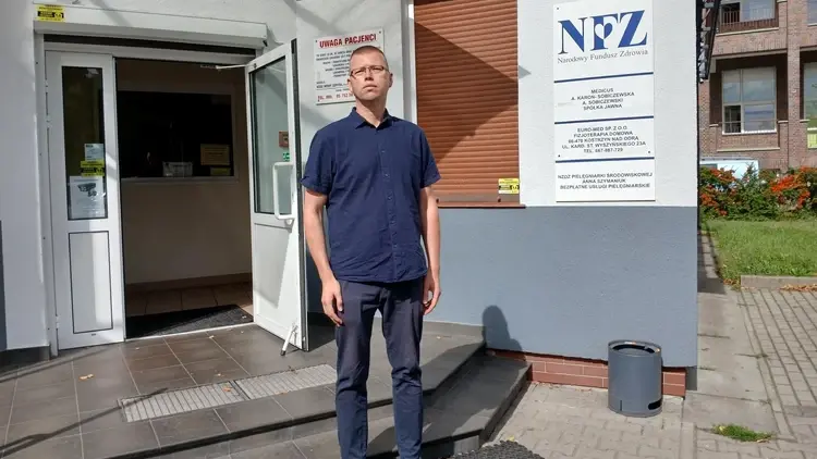 Mężczyzna stoi przed placówką NFZ