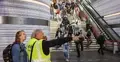 Tłum ludzi na dworcu, mężczyzna pokazuje palcem