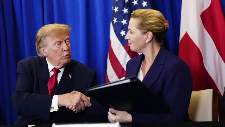Donald Trump i Mette Frederiksen ściskają swoje dłonie, w tle flaga USA i Danii