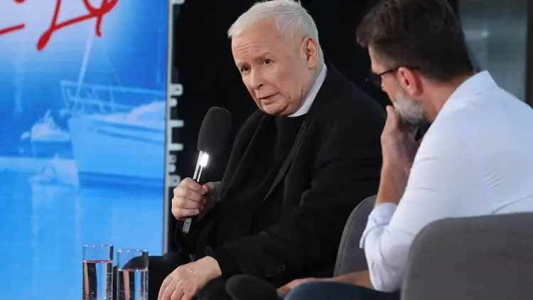 Jarosław Kaczyński przemawia do mikrofonu, obok mężczyzna w białej koszuli