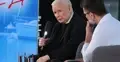 Jarosław Kaczyński przemawia do mikrofonu, obok mężczyzna w białej koszuli