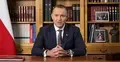 Karol Nawrocki przemawia na siedząco na tle biblioteczki i polskiej flagi