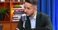 Jakub Wiech mówi do mikrofonu, w tle biblioteczka i niebieska kotara