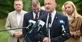 Mariusz Błaszczak przemawia do mikrofonu na konferencji prasowej. W tle ludzie