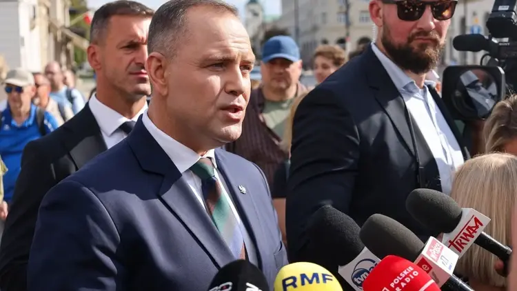 Karol Nawrocki przemawia do dziennikarzy. W tle ludzie