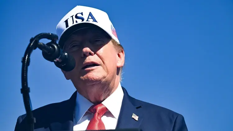 Donald Trump w czapce przemawia do mikrofonu