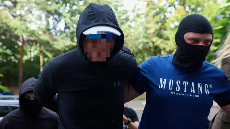 Aresztowany mężczyzna w bluzie z kapturem z zasłoniętą twarzą