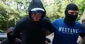 Aresztowany mężczyzna w bluzie z kapturem z zasłoniętą twarzą